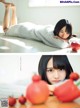 A woman laying on top of a bed next to a bunch of tomatoes.