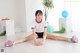 A young woman sitting on the floor with her legs crossed.