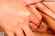 A close up of a person's hand touching a woman's eye.