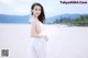 A woman in a white dress standing on a beach.