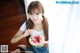 A young woman eating a slice of watermelon with a spoon.