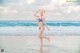 A woman in a bikini standing in the ocean.