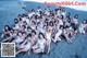 A group of women in white bathing suits posing for a picture on the beach.