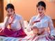 A couple of women sitting on top of a bed.