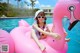 A woman sitting on an inflatable pink flamingo in a pool.