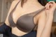 A woman wearing a gray bra with a black lace trim.